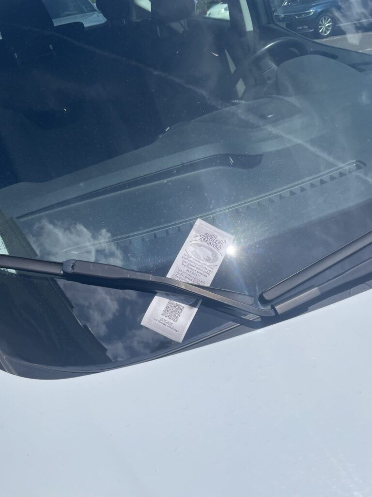Wlepka z informacją o Baranku za wycieraczką samochodu